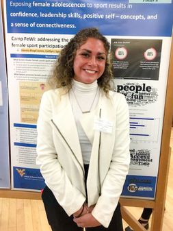 Portrait of Caitlyn Lyons in front of her poster on research day