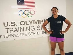 Kanchana standing in front of a sign for a US Olympics training site