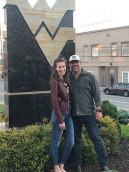 Catherine O'Malley poses with her husband in front of a marble flying WV.