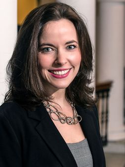 Dana Voelker with shoulder length dark brown hair, wearing a necklace, dark jacket and grey blouse. 