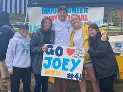 Five student members of Morgan's Message are holding a poster saying "Go Joey WVU."