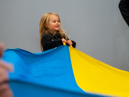 A young student from the WVU Nursery School holds the edge of a parachute.