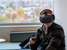 A student sits with a virtual reality headset with fall foliage in the background.