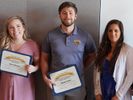 Three WVU students stand holding certificates after earning awards from CPASS