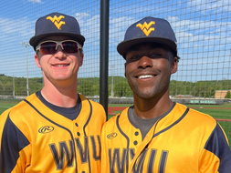 Anthony Richards stands for a photo with his WVU baseball club teammate at a baseball field.