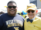 Jihad Dixon in sunglasses and a blue WVU t-shirt stands next to Dr. Gordon Gee in sunglasses, a hat and signature bow tie.