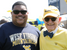 Jihad Dixon in sunglasses and a blue WVU t-shirt stands next to Dr. Gordon Gee in sunglasses, a hat and signature bow tie.
