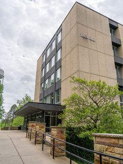 Allen Hall main entrance with sidewalk leading to covered glass doors. 